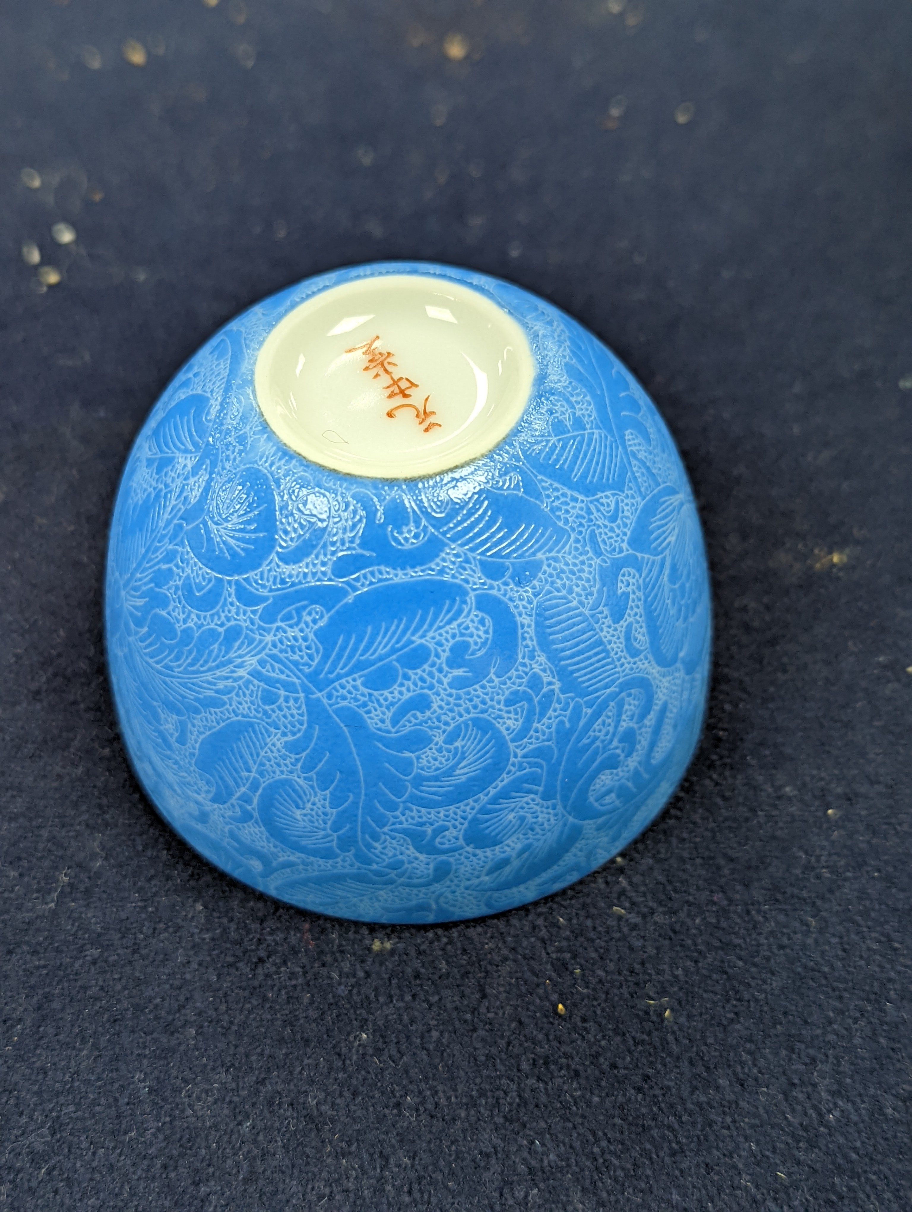 A Japanese or Chinese sgrafitto blue enamelled cup, cased. 6cm diameter